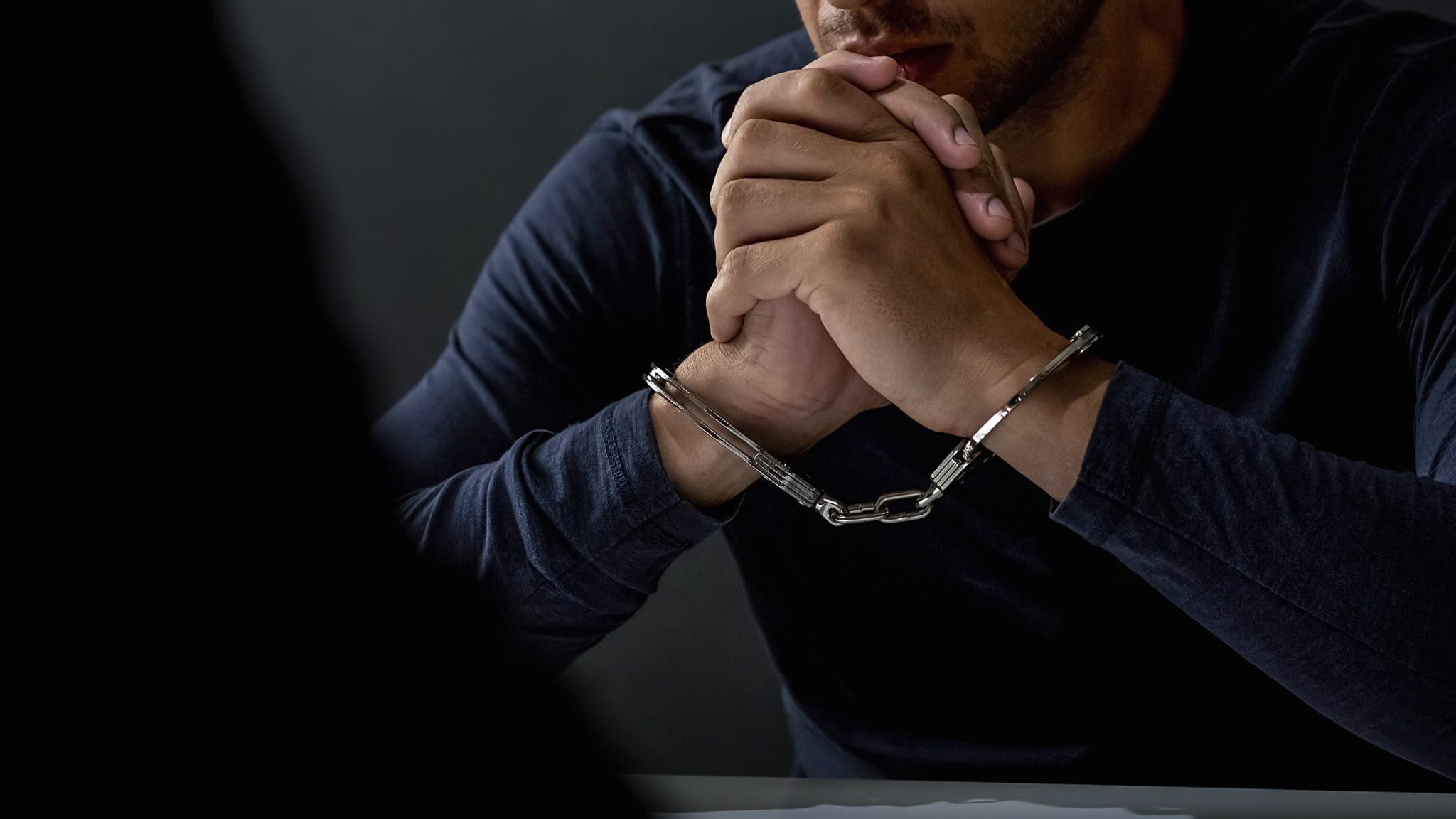 Criminal man with handcuffs in interrogation room Criminal man with handcuffs in interrogation room feeling guilty after committed a crime